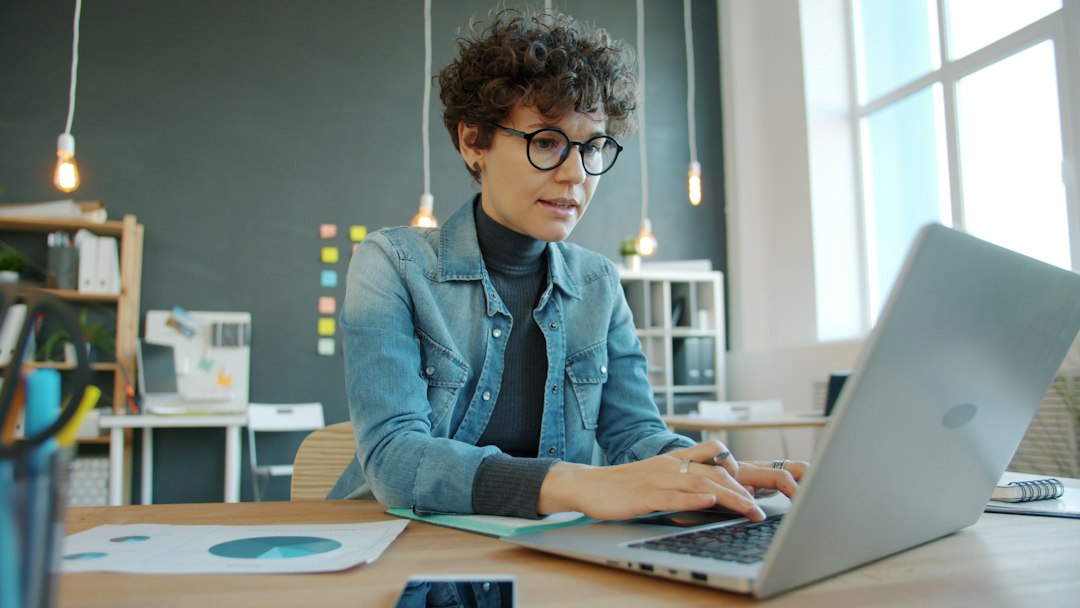 Une acheteuse à son bureau fait une recherche sur son ordinateur portable.