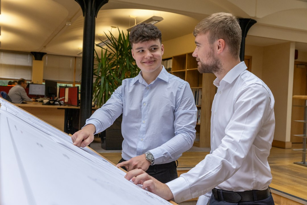 Deux ingénieurs examinent un grand plan dans les bureaux d’un bureau d’études.