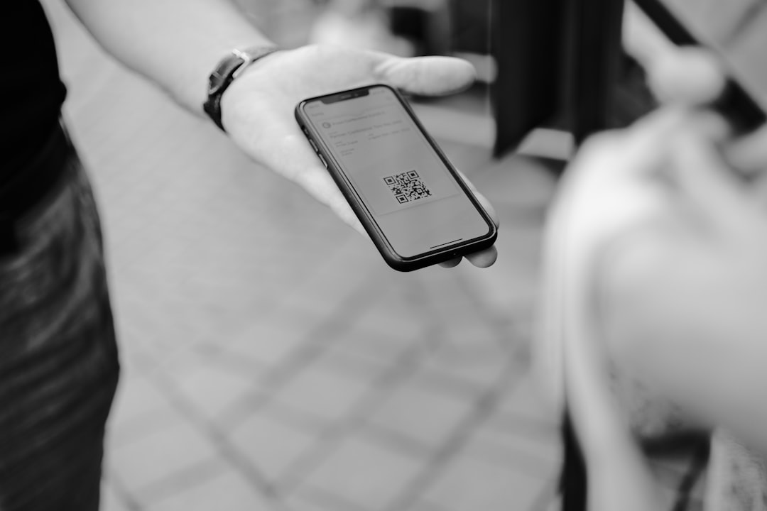 Hand holding a smartphone displaying a Google review request, with a QR code in the background.