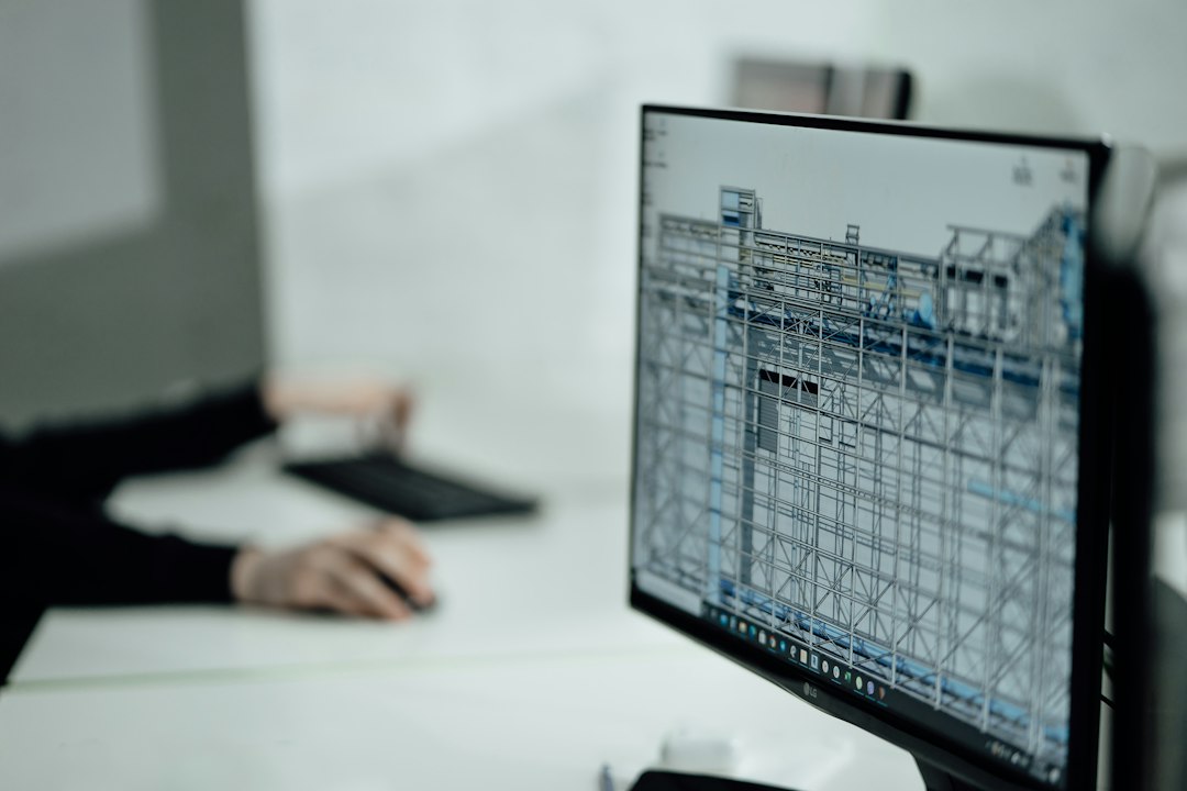 Un écran affiche la maquette 3D d’une structure de bâtiment, devant un ingénieur à son poste.