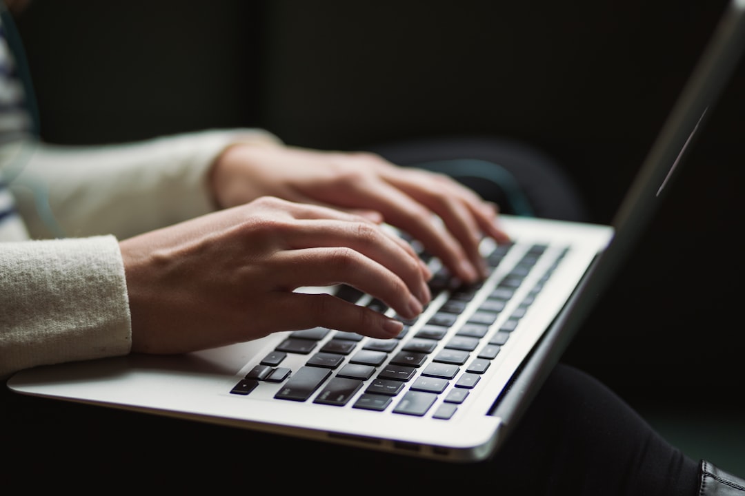 Personne concentrée rédigeant une réponse professionnelle sur ordinateur, dans un bureau aux tons bleus et blancs.