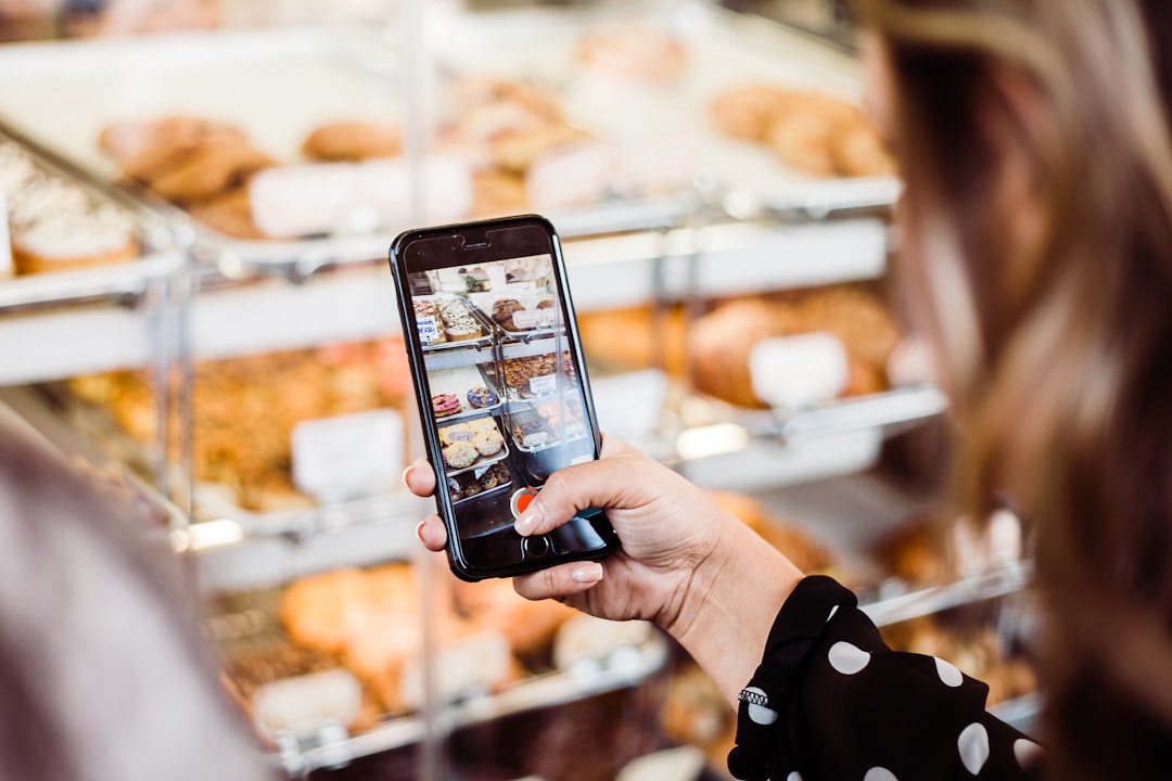 Un entrepreneur photographie l'intérieur chaleureux de son commerce avec un smartphone pour sa fiche Google My Business.