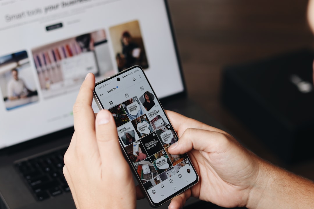 Person using a smartphone, showing comments and likes on social media, in a modern setting.
